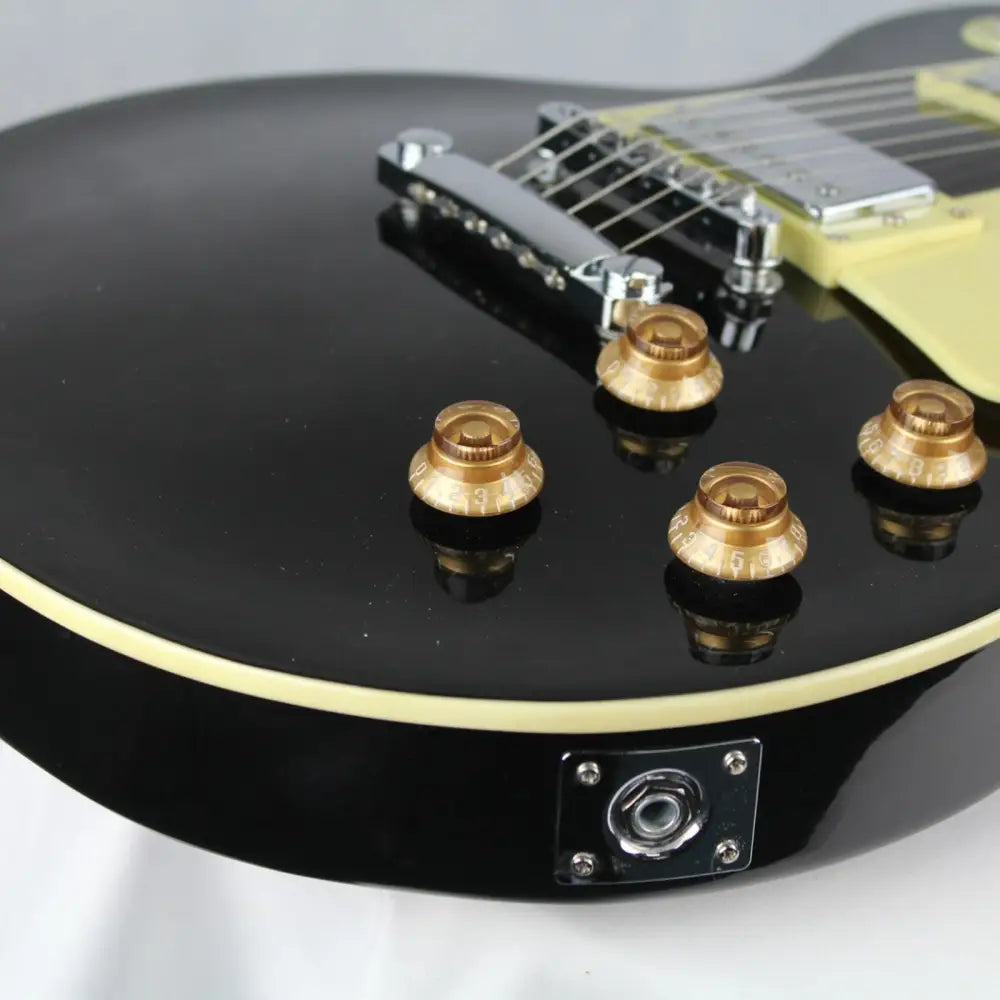 Black electric guitar with gold knobs and chrome hardware, perfect beginner LP style guitar