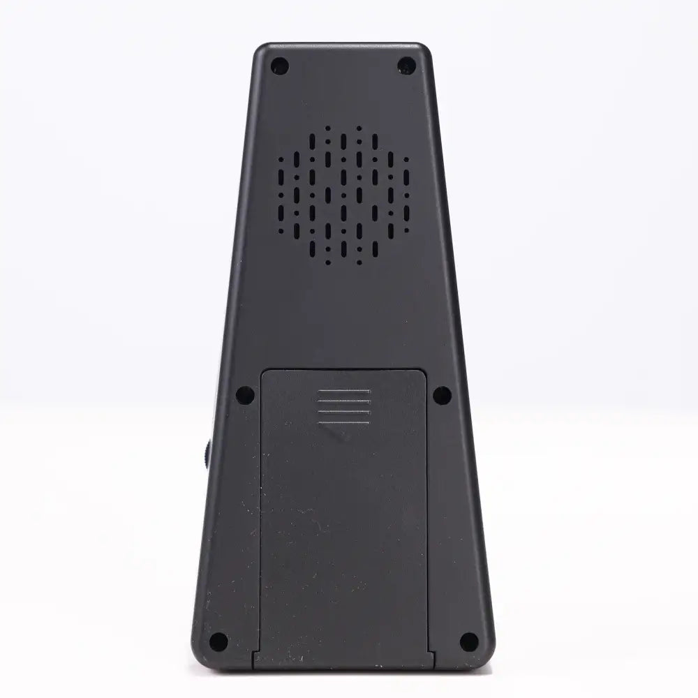 Back side of a black plastic axiom digital metronome showing perforated speaker grille and battery compartment
