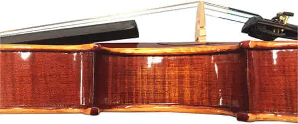 Close-up view of the side of a polished wooden violin with part of the bridge, strings, and bow visible above.