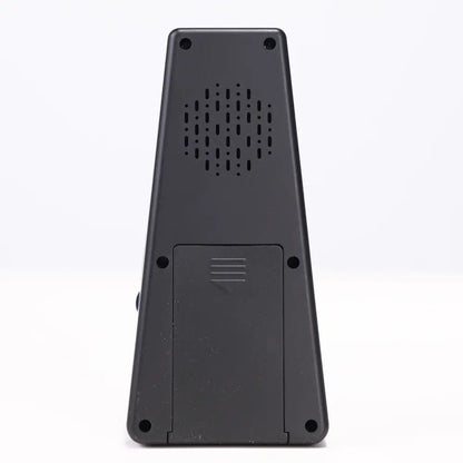 Back side of a black plastic axiom digital metronome showing perforated speaker grille and battery compartment