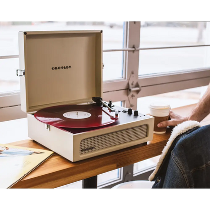 Cream-colored Crosley Voyager Dune Bluetooth Portable Turntable with red vinyl record