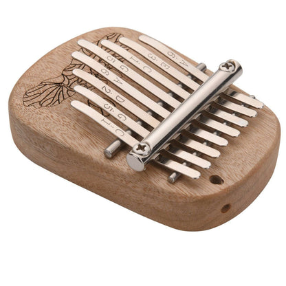 The Axiom Kalimba Thumb Piano by Axiom Music is crafted from camphor wood with an engraved floral design, labeled metal tines for notes and numbers, and comes with a tuning hammer for easy adjustments.