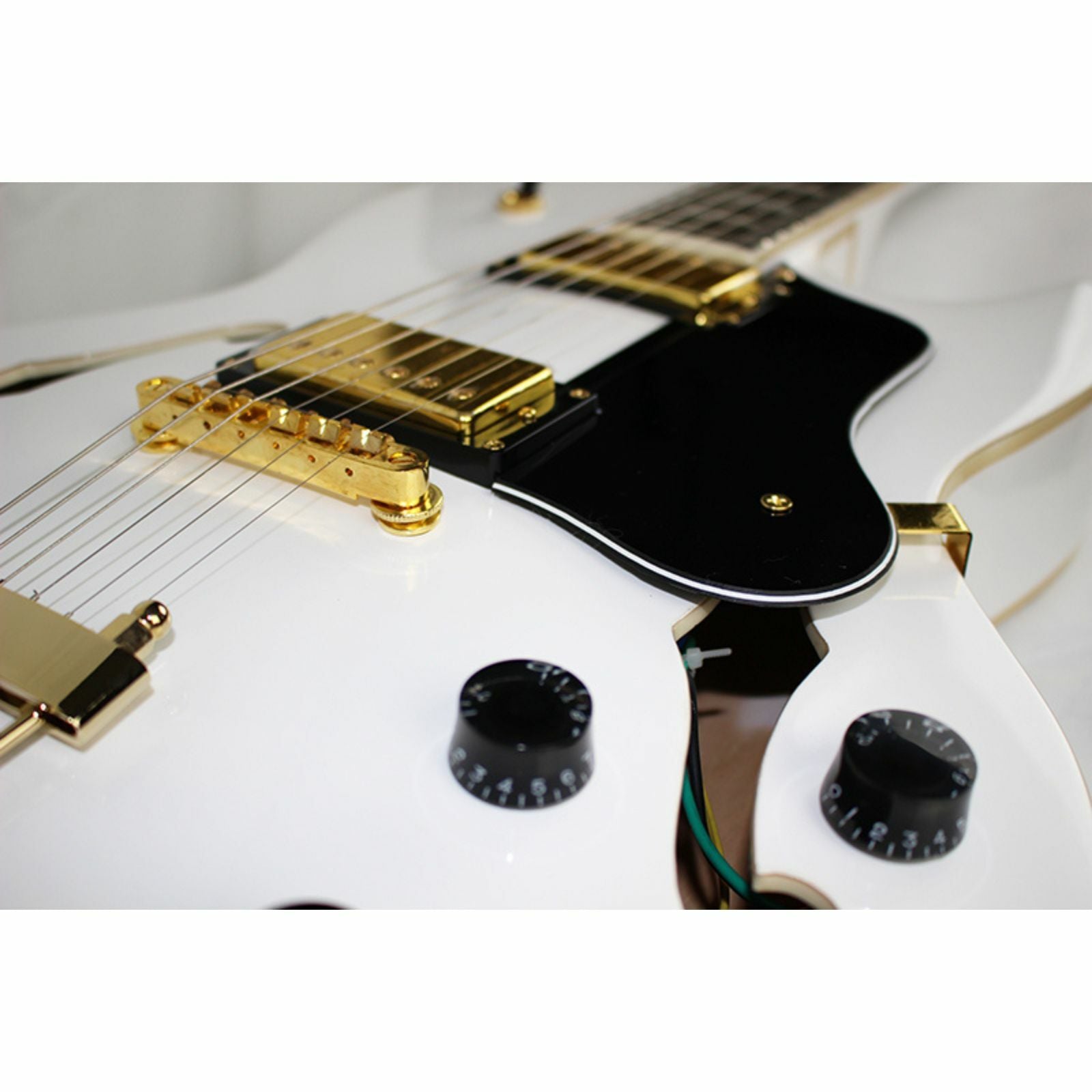 The Axiom Music Axiom Columbia Archtop Electric Guitar White Bird features a white hollow body, gold hardware, black pickguard, vintage-style humbuckers, four knobs, two pickups, and f-hole cutouts.
