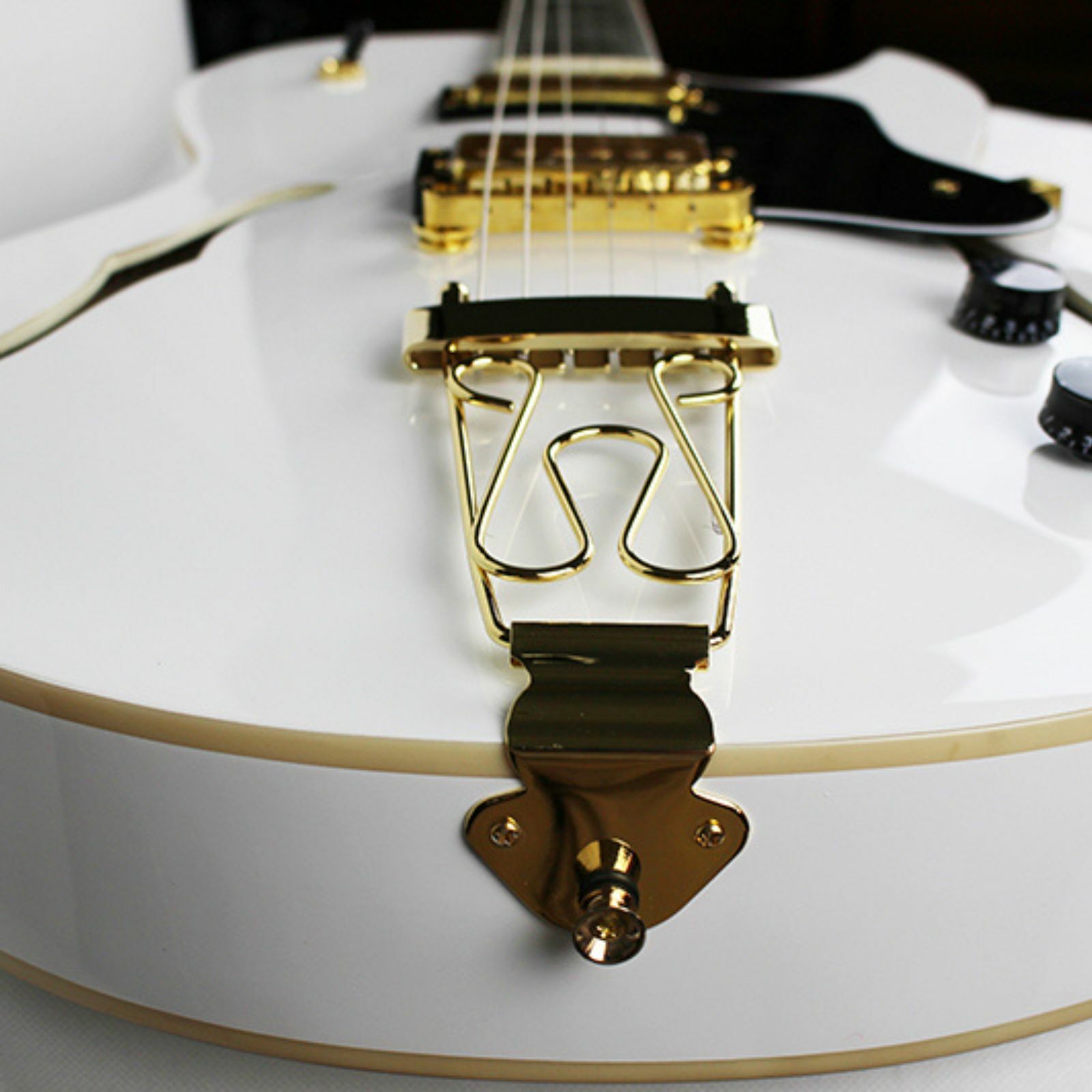 The Axiom Music Axiom Columbia Archtop Electric Guitar White Bird features a white hollow body, gold hardware, black pickguard, vintage-style humbuckers, four knobs, two pickups, and f-hole cutouts.
